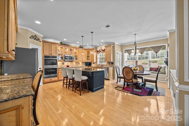 1900 Birchbrook Ct, Harrisburg, NC 28075 - kitchen with stainless steel appliances, a kitchen breakfast bar, ornamental molding, a center island, and glass insert cabinets