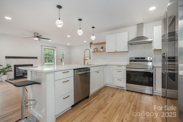 6301 Vernedale Rd, Charlotte, NC 28212 - kitchen featuring stainless steel appliances, wall chimney exhaust hood, a sink, a peninsula, and light countertops