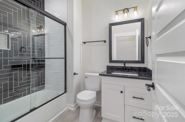 bathroom featuring combined bath / shower with glass door, vanity, toilet, and baseboards