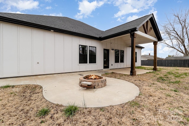 rear view of property featuring an outdoor fire pit, board and batten siding, fence, a patio, and roof with shingles