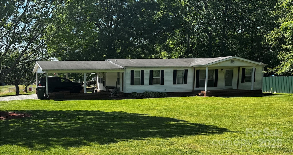single story home with covered porch, gravel driveway, a front yard, and an attached carport