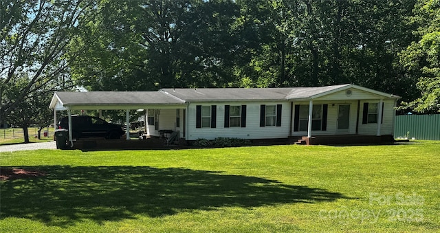 single story home with covered porch, gravel driveway, a front yard, and an attached carport