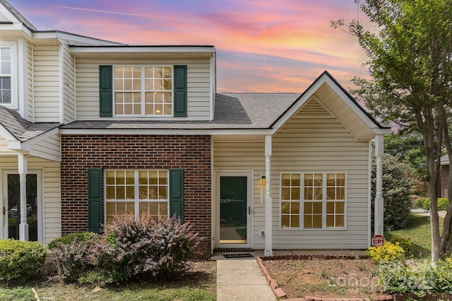 view of front of home with roof with shingles and brick siding