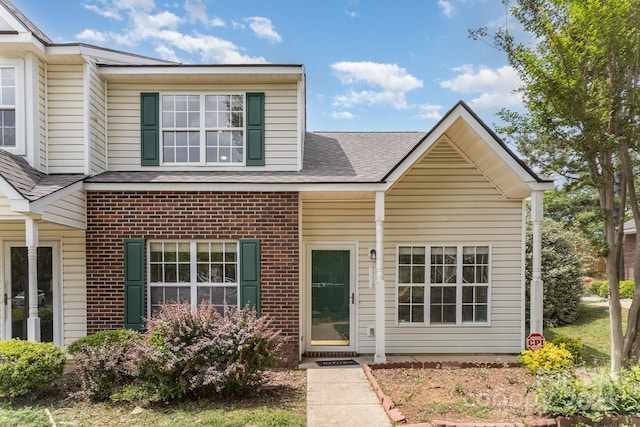 view of front of home featuring brick siding and roof with shingles