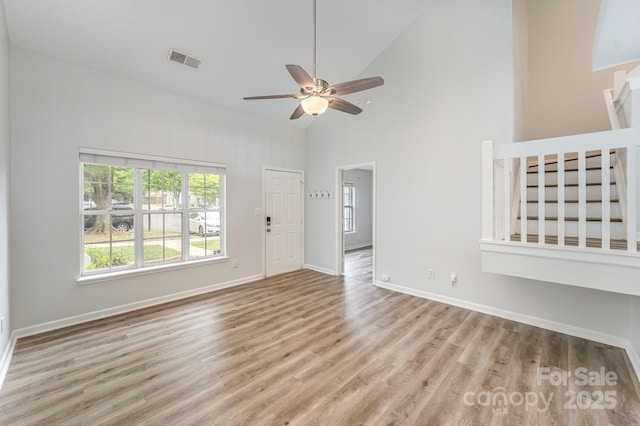 unfurnished living room featuring ceiling fan, high vaulted ceiling, baseboards, wood finished floors, and visible vents