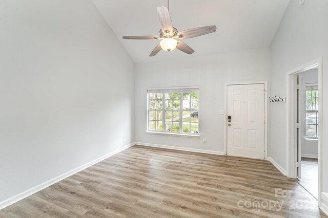 interior space with light wood-style floors, high vaulted ceiling, ceiling fan, and baseboards
