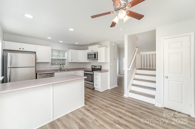 kitchen featuring light wood-style floors, ceiling fan, light countertops, white cabinetry, and appliances with stainless steel finishes