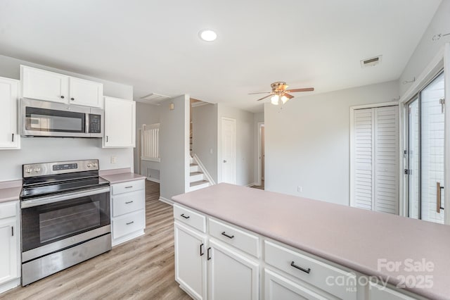kitchen with visible vents, light countertops, a ceiling fan, light wood finished floors, and appliances with stainless steel finishes