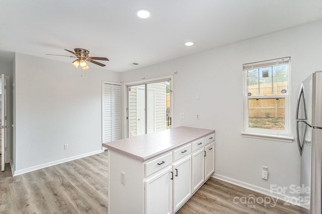 kitchen featuring ceiling fan, freestanding refrigerator, a peninsula, white cabinetry, and baseboards