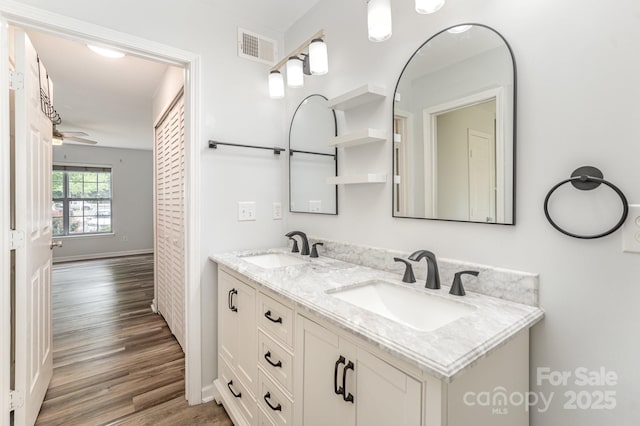 bathroom with double vanity, a sink, wood finished floors, and visible vents