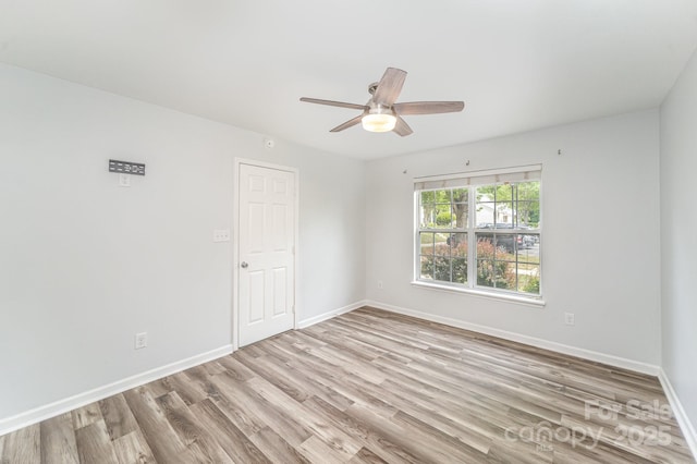 empty room featuring a ceiling fan, baseboards, and light wood-style floors