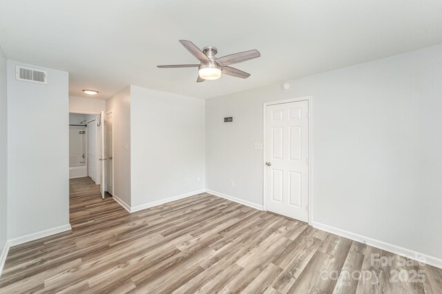 empty room with baseboards, ceiling fan, visible vents, and wood finished floors