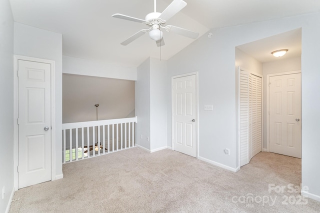 empty room with carpet flooring, ceiling fan, vaulted ceiling, and baseboards