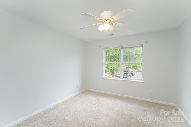 spare room with baseboards, ceiling fan, visible vents, and light colored carpet