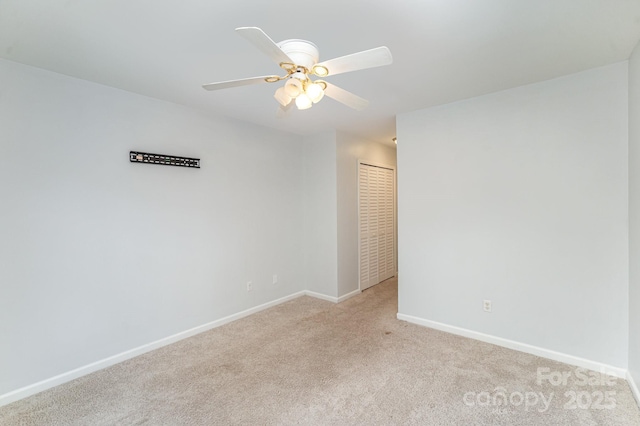 spare room with ceiling fan, light carpet, and baseboards