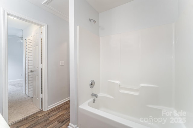 bathroom with baseboards, shower / bathtub combination, and wood finished floors