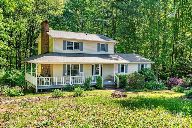 farmhouse-style home with a wooded view, covered porch, and a chimney