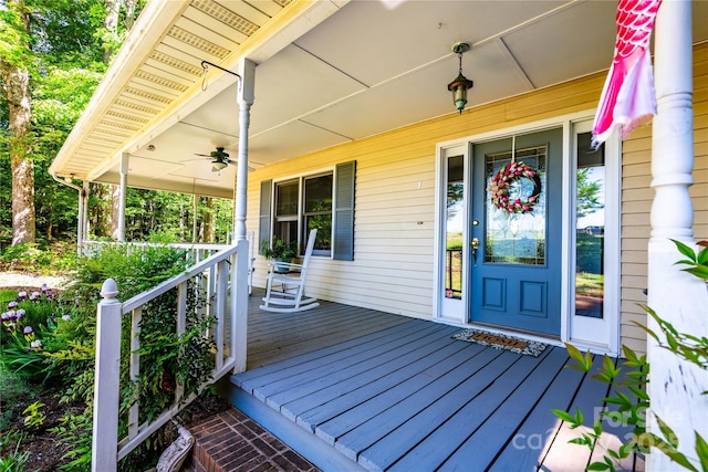 wooden terrace with covered porch and a ceiling fan