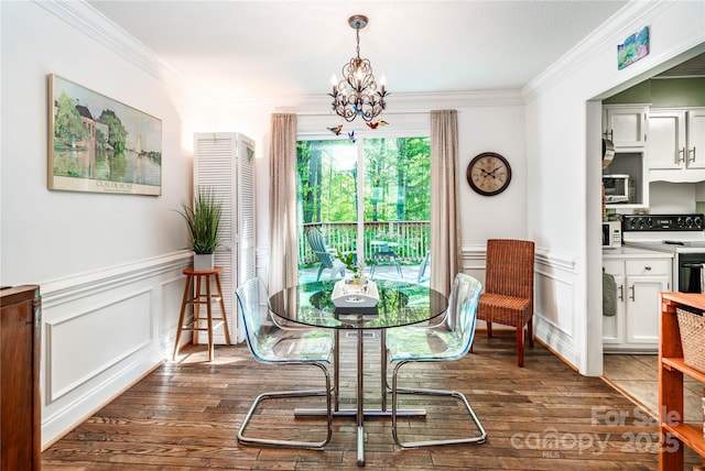 dining area with an inviting chandelier, ornamental molding, a decorative wall, and dark wood-type flooring