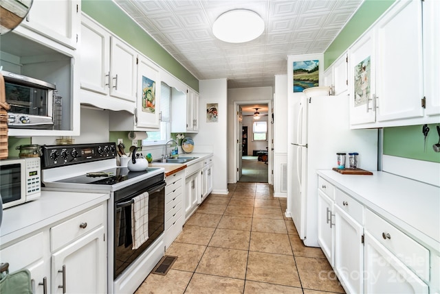 kitchen with white appliances, an ornate ceiling, light countertops, white cabinets, and a sink
