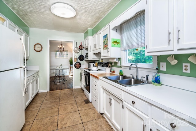 kitchen with white cabinets, an inviting chandelier, a sink, white appliances, and light countertops