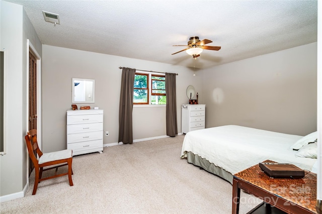 bedroom featuring light carpet, a textured ceiling, a ceiling fan, baseboards, and visible vents