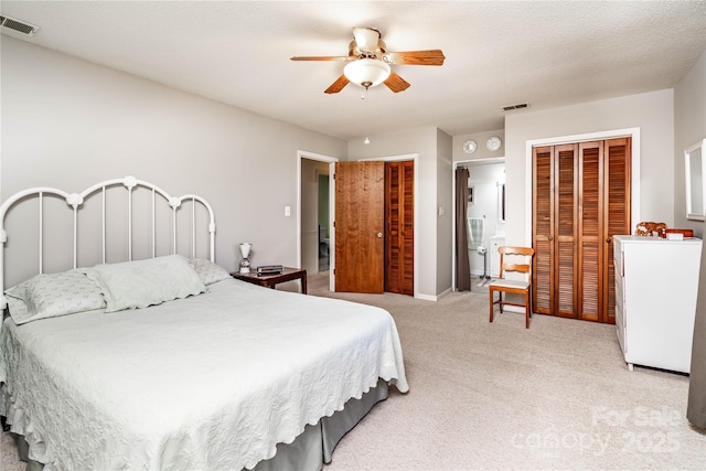 bedroom featuring multiple closets, ceiling fan, light carpet, and visible vents