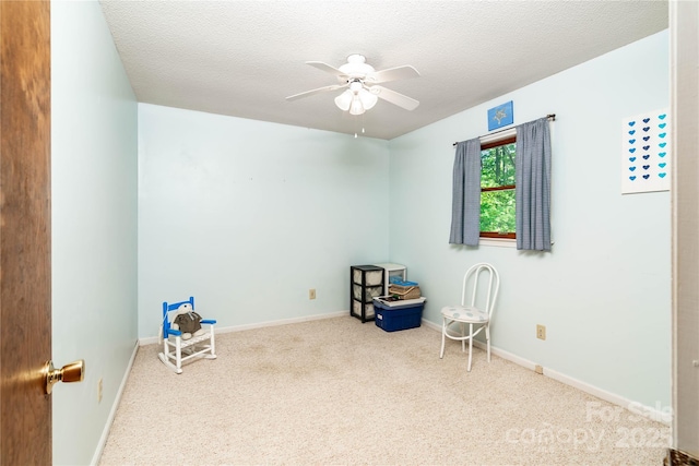 recreation room with carpet floors, ceiling fan, baseboards, and a textured ceiling