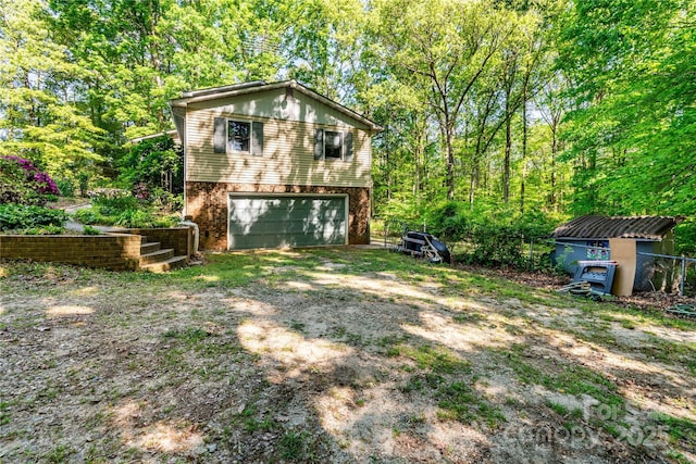 rear view of house featuring brick siding, dirt driveway, a garage, and a storage unit