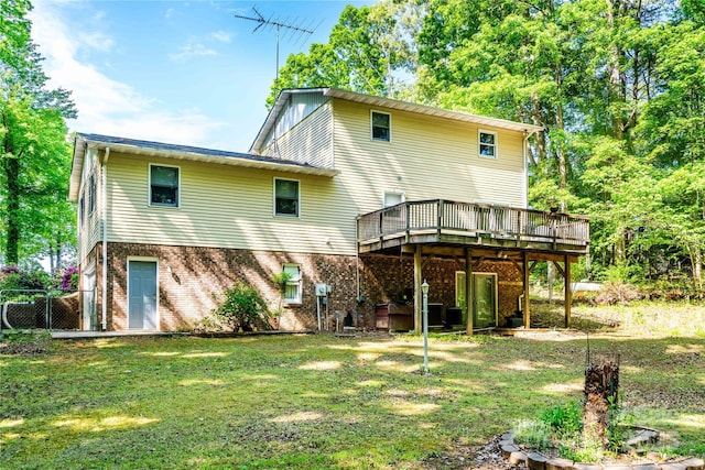 back of property featuring a lawn, fence, a wooden deck, and brick siding