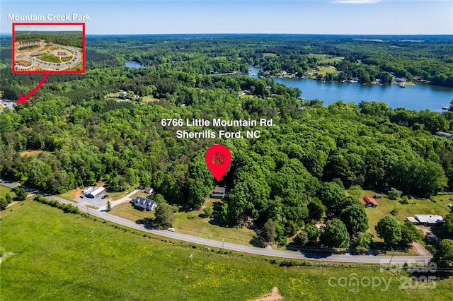 aerial view featuring a forest view and a water view