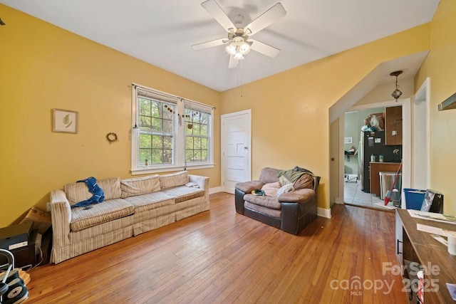 living room featuring wood-type flooring, ceiling fan, and baseboards