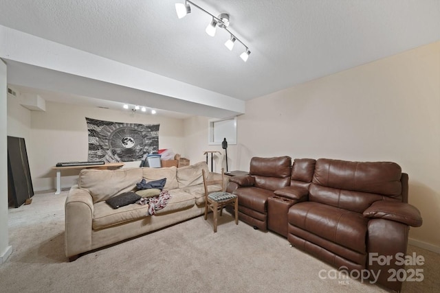 carpeted living room with a textured ceiling, rail lighting, and baseboards