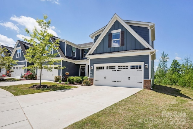 craftsman house with a front lawn, stone siding, a garage, board and batten siding, and driveway