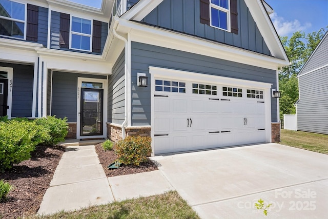 exterior space featuring board and batten siding, concrete driveway, stone siding, and a garage