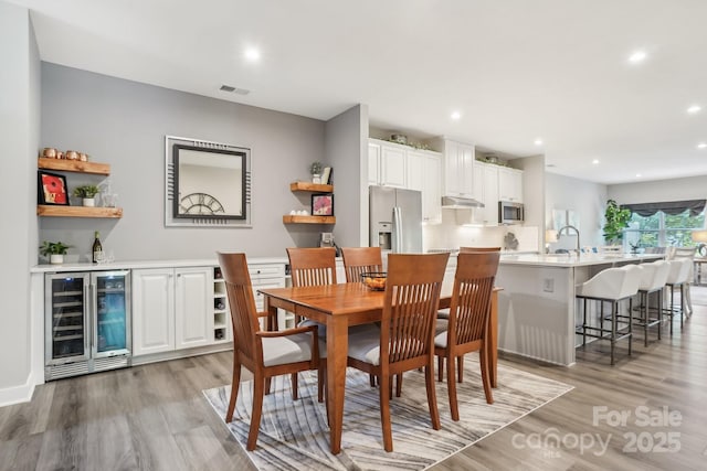 dining room with light wood-style floors, visible vents, a dry bar, and wine cooler