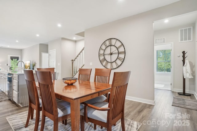 dining room featuring recessed lighting, plenty of natural light, light wood finished floors, and stairs