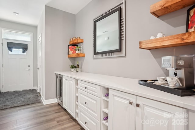bar featuring baseboards, light wood-style flooring, and wine cooler