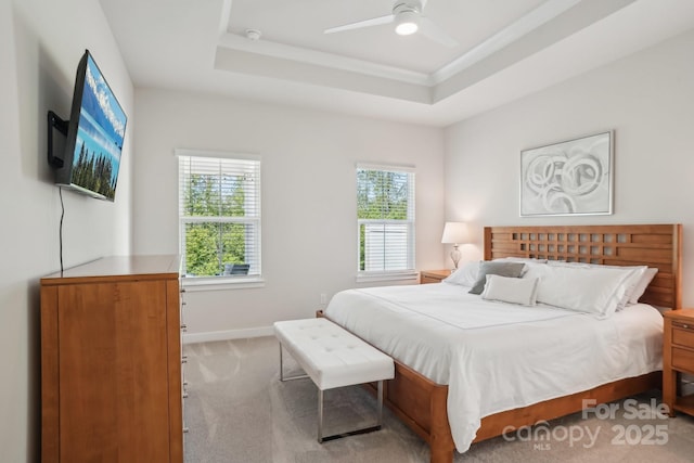 carpeted bedroom featuring a ceiling fan, baseboards, and a raised ceiling