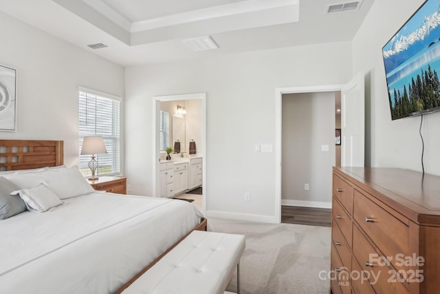 bedroom with baseboards, light carpet, connected bathroom, and visible vents