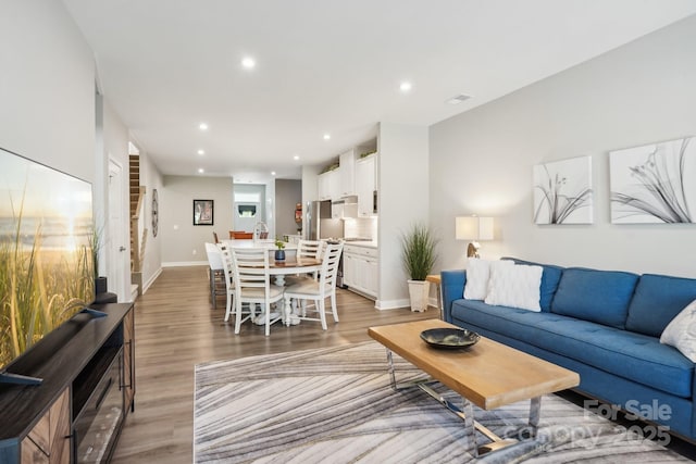 living area featuring light wood-style floors, baseboards, and recessed lighting