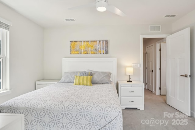 bedroom featuring light colored carpet, a ceiling fan, and visible vents