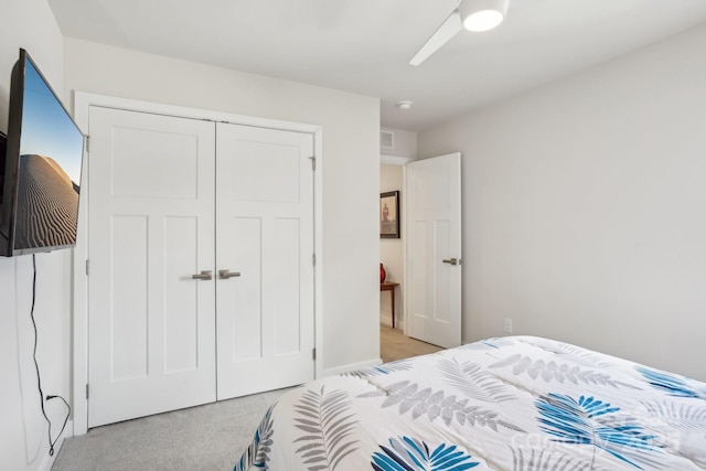 bedroom with ceiling fan, light carpet, and a closet