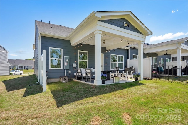 rear view of property featuring a lawn, fence, and a patio