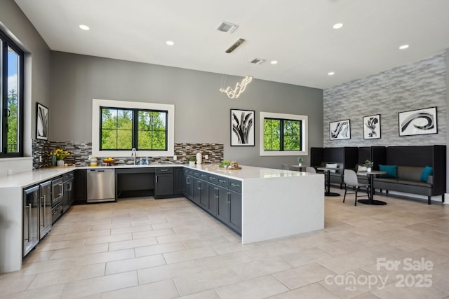 kitchen featuring stainless steel dishwasher, a peninsula, visible vents, and a healthy amount of sunlight