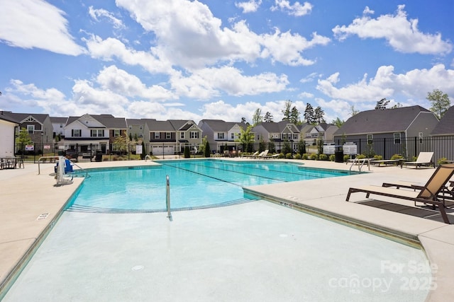 community pool with a residential view, fence, and a patio