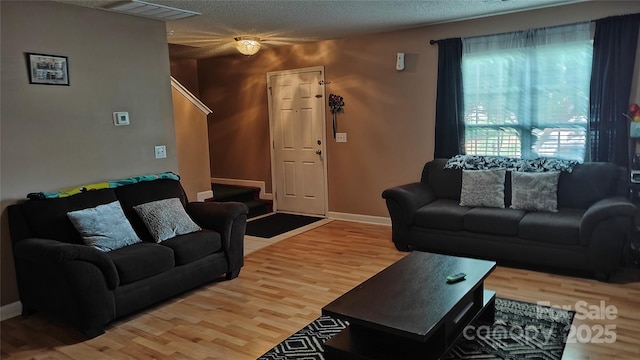 8524 Stoneman Pl, Charlotte, NC 28217 - living area with a textured ceiling, light wood-style flooring, stairs, baseboards, and visible vents