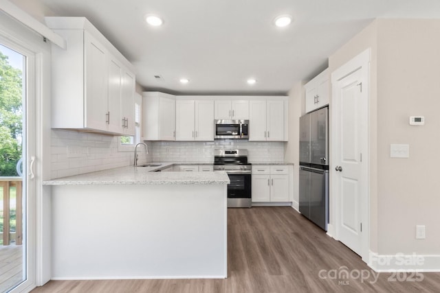 236 Elizabeth Ave, Forest City, NC 28043 - kitchen with backsplash, wood finished floors, a sink, a peninsula, and stainless steel appliances