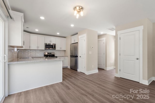 236 Elizabeth Ave, Forest City, NC 28043 - kitchen featuring appliances with stainless steel finishes, white cabinets, a peninsula, and wood finished floors
