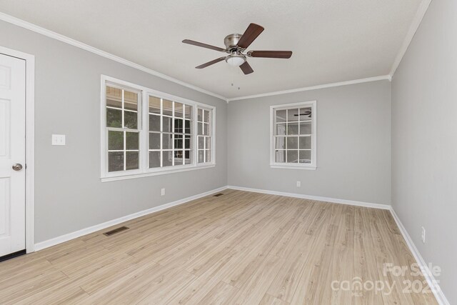 spare room with light wood-style floors, a ceiling fan, baseboards, visible vents, and ornamental molding
